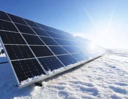 Solar panels in a snowy landscape with the sun brightly shining, illustrating efficient solar power generation in winter.