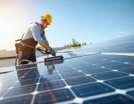 Technician cleaning solar panels on a commercial rooftop using specialized equipment to maintain optimum efficiency.
