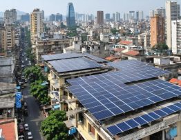A bustling cityscape in an emerging market showcasing solar panels on skyscrapers, industrial facilities, and residential buildings, illustrating the integration of solar energy into urban infrastructure.