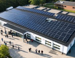 Aerial view of a modern school with solar panels on the roof, illustrating the integration of renewable energy in educational environments.