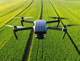 A solar-powered agricultural drone with solar panels on its wings hovering over a vast green crop field under a clear sky, symbolizing the integration of innovative technology into modern farming practices.