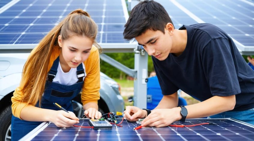 Students conducting solar project experiments with solar panels and charging stations, illustrating renewable energy education.