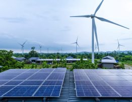 "A sustainable community with solar panels and wind turbines amidst green landscapes, promoting integrated renewable energy systems."
