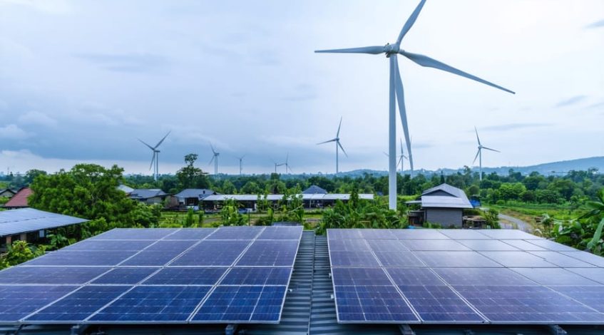 "A sustainable community with solar panels and wind turbines amidst green landscapes, promoting integrated renewable energy systems."