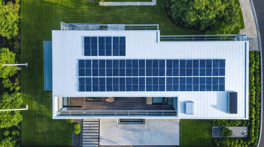"Contemporary residential home with solar panels on the roof, showcasing advanced energy technology in a suburban setting."
