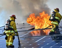 Firefighters in protective gear responding to a solar panel emergency, using advanced equipment and adhering to safety protocols, with visible safety zones and hazard warnings.
