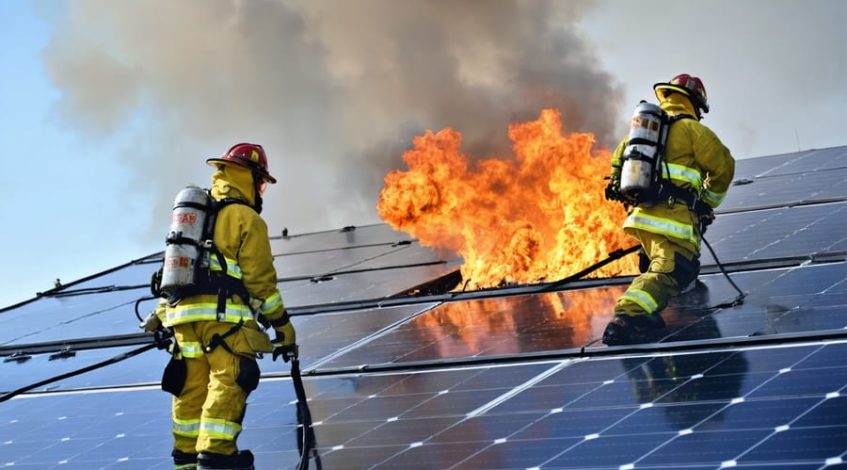 Firefighters in protective gear responding to a solar panel emergency, using advanced equipment and adhering to safety protocols, with visible safety zones and hazard warnings.