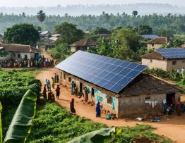 "A Tanzanian village with solar panels on homes, set against lush greenery and traditional architecture, representing the integration of sustainable energy."